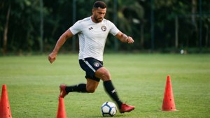 Soccer player dribbling ball between orange cones on grass field