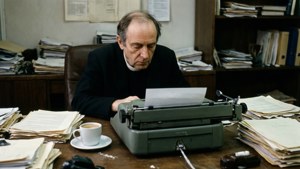 Foucault travaillant sur une machine à écrire à un bureau en désordre dans un bureau des années 1970.