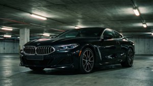 BMW Série 8 noire dans un garage souterrain avec un éclairage d'ambiance