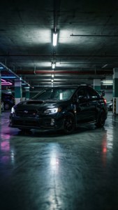 A black Subaru WRX STI in a dark underground parking lot with dramatic lighting. — Subaru Background