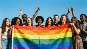 Groupe diversifié tenant le drapeau de la fierté au soleil, unité et joie.