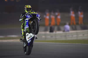 Motorcycle racer doing a wheelie on a racetrack at night. — Motorsport Wallpaper