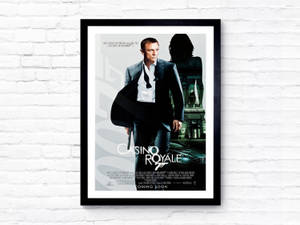 Framed Casino Royale movie poster on a white brick wall.