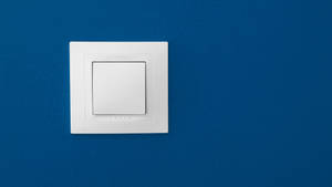 White light switch mounted on a textured blue wall.