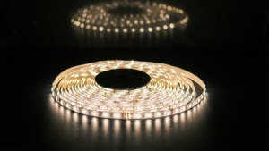 Tira de LED enrollada que emite luz blanca cálida sobre superficie negra, forma espiral
