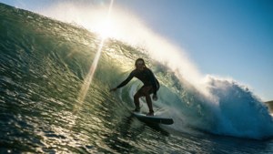 Surfer riding a big wave with sun flare. — Ocean Picture