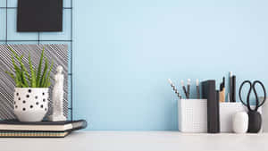 Minimalist desk with plant books and stationery against blue wall — Webex Background