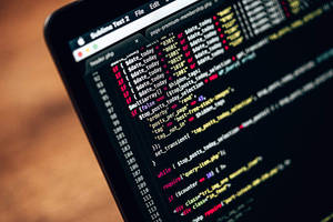 Laptop-Bildschirm zeigt PHP-Code mit farbenfroher Syntaxhervorhebung auf Holztisch.