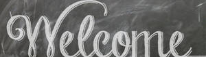 Handwritten welcome message in white chalk on a dark chalkboard surface. — Green Chalkboard Background