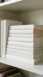 Ordentlicher Stapel weißer Bücher auf einem Regal, minimalistisches Bücherliebhaber-Wallpaper.