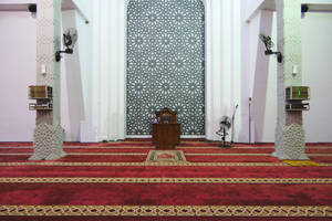 Interior de mezquita con alfombra roja, púlpito de madera y pantalla geométrica. — Fondods anchos Fondo Fondos de pantalla