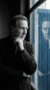 Kontemplativt portræt af Peter Finch ved et vindue
