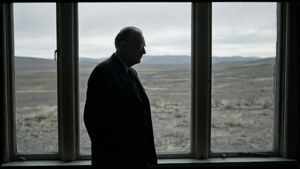 Oppenheimers silhuet ved et vindue, der ser ud på en gold verden.