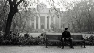 Svart-hvitt bilde av en student på en benk ved Delhi University-biblioteket i vinterdis