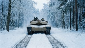 Leopard 2A7 in verschneitem Wald mit frischen Spuren, ruhige Winterlandschaft.