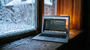 En MacBook Air på en snöig fönsterbräda med mysig inomhusbelysning.