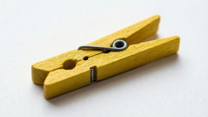 Et detaljeret makro-billede af en gul tøjklemme på hvid baggrund.