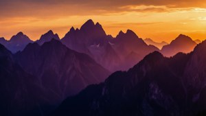 Dramaattinen violetti ja oranssi siksak-vuoren siluetti taustakuva auringonlaskun hehkulla